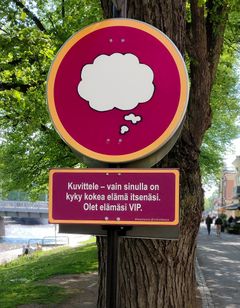 Pyöreän ja suorakaiteen muotoiset viininpunaiset kyltit puussa.