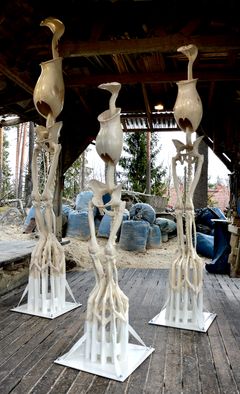 Kolme luurankomaista vaaleaa hahmoa seisomassa.