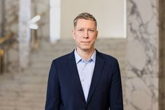 Vakava mies katsoo kameraan puku päällä.