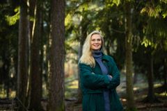 Nainen seisoo metsässä ja katsoo kameraan