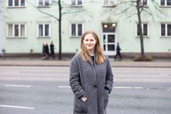 Nainen seisoo kadun varressa ja katsoo kameraan