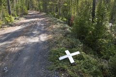 En somrig bild av ett skogigt område med en grusväg som går genom mitten. Vid grusvägens kant syns en vit flygsignal.