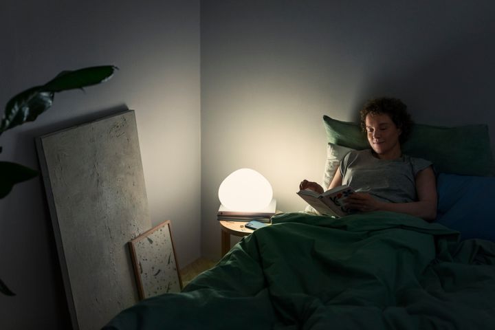 Nainen lukee yölampun valossa kirjaa.