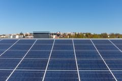 Aurinkosähköpaneeleita katolla. Kaupungin metsä ja taloja taustalla.