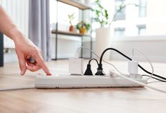 Valkoinen pistorasia, jossa sähköjohtoja