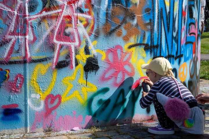 Lapsi spraymaalaa värikästä seinää