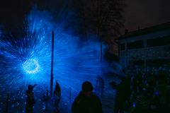 Kuvan alt-teksti: Sinisävyinen valotaideteos "Divine Geometry" valaisee pimeää ulkotilaa, ympärillä ihmisiä katselemassa.