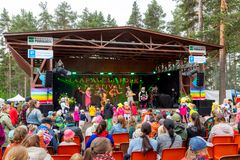 Kuvassa lastenmusiikkiorkesteri esiintyy ulkolavalla metsäisellä alueella Haapavesi Folk -festivaalin Lastenpäivässä 2023. Paikalla paljon yleisöä, erityisesti lapsiperheitä.