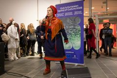 Nainen esiintyy perinteisessä asussa mikrofonin kanssa Oulun taidemuseolla.