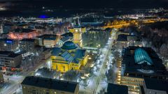 Aerial night view of Oulu Cathedral, illuminated with surrounding city lights and buildings.