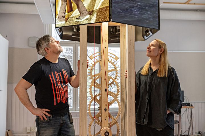 Oliver Kochta-Kalleinen ja Tellervo Kalleinen katsovat ylöspäin näyttöä, jossa on taideteos.