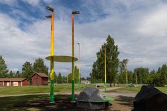 Katuvaloja, penkkejä ja kiviä maalattu vihreän, keltaisen, oranssin ja punaisen sävyillä Oulunsalon Lentokentäntiellä.