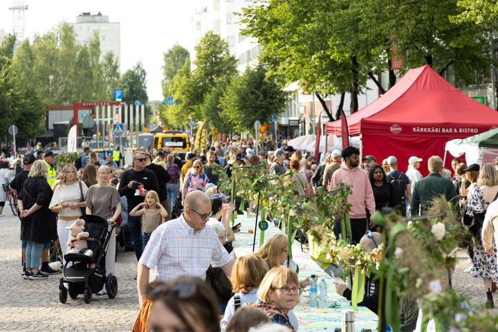 Kuva kadulta, ihmisiä ja pitkä pöytä