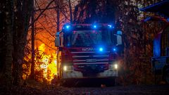 Tulipalon loimussa metsän keskellä seisova paloauto savusukellusharjoituksessa.