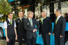Kuvassa viisi Nobina Oy:llä työskentelevää linja-autonkuljettajaa kuvattuna sinisen HSL:n bussin edessä.