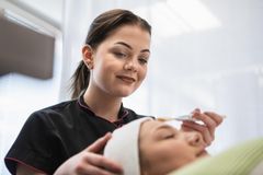Kosmetologi tekee asiakkaalle kasvohoitoa.