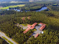 Iso koulurakennus, metsää ja joki.