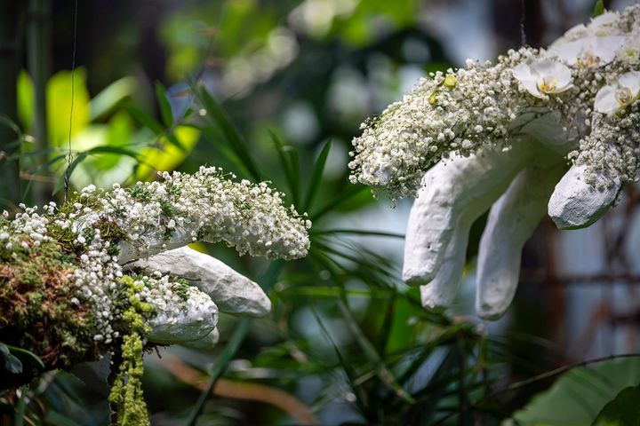 Kädet, jotka on maalattu valkoisiksi ja koristeltu kukilla.