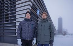 Kaksi miestä seisoo sumuisessa peltomaisemassa.