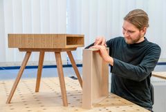 Puuseppä työskentelee puisen huonekalun parissa verstaassa.