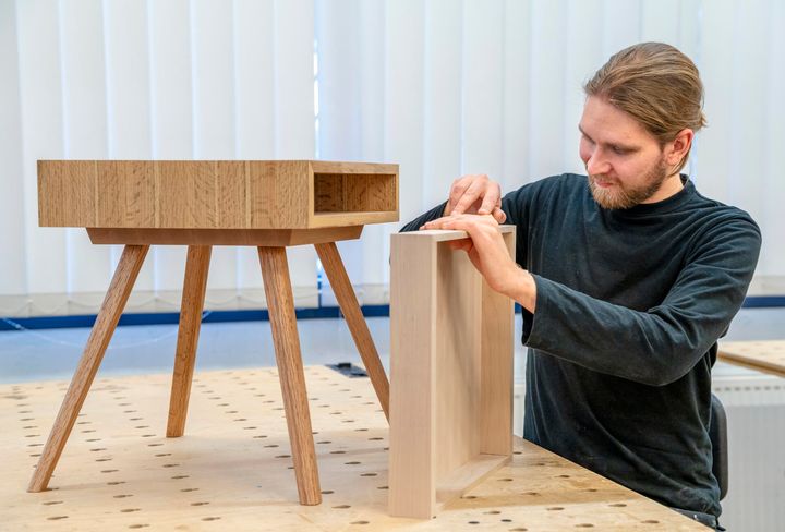 Puuseppä työskentelee puisen huonekalun parissa verstaassa.