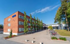 Punatiilinen rakennus Kotkantiellä, vieressä pyörätelineitä ja puita.