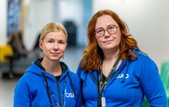 Kaksi henkilöä seisoo vierekkäin sinisissä huppareissa, joissa on OSAO-logo.