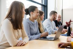 Ryhmä ihmisiä istuu pöydän ääressä keskustelemassa. Edessä on kannettava tietokone.