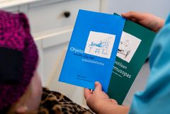 Henkilö pitelee kahta opasta saattohoidosta ja syöpähoidosta.