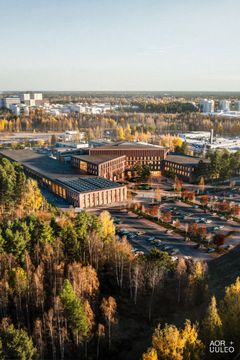 Ilmakuva syksyisestä kampusalueesta, jonka ympärillä on puita ja pysäköintialueita.