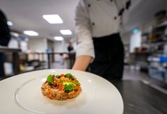 Kokki tarjoilee kauniisti asetellun annoksen lautasella ravintolan keittiössä.