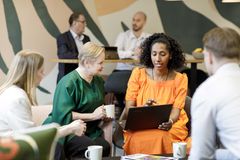 Ryhmä ihmisiä keskustelee yhdessä toimistotilassa. Etualalla naiset keskustelevat kannettavan tietokoneen äärellä.