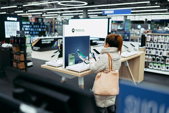 Nainen tutkii Motorola-merkkistä puhelinta Gigantin myymälässä.