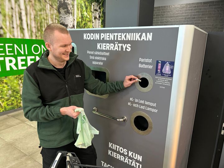Mies palauttaa käytöstä poistettuja paristoja kaupan keräyspisteellä