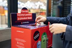 Henkilö laittaa käytetyn pariston keräyslaatikkoon.