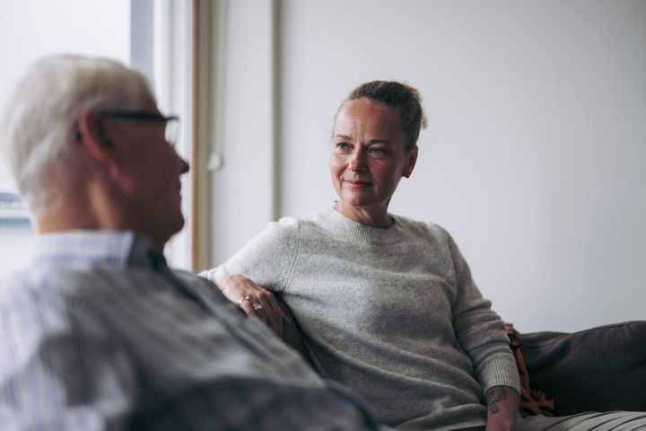 Kaksi henkilöä istuu sohvalla keskustellen.