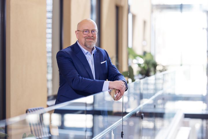 Thomas Hietto kuvattuna toimistolla suuren ikkunan edessä.