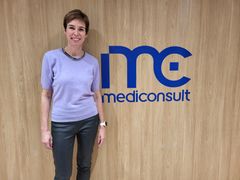 Mediconsultin myynti- ja asiakkuusjohtaja Laura Virros seisoo seinää vasten. Seinän  pinta näyttää puulta ja siinä on Mediconsultin sininen logo.