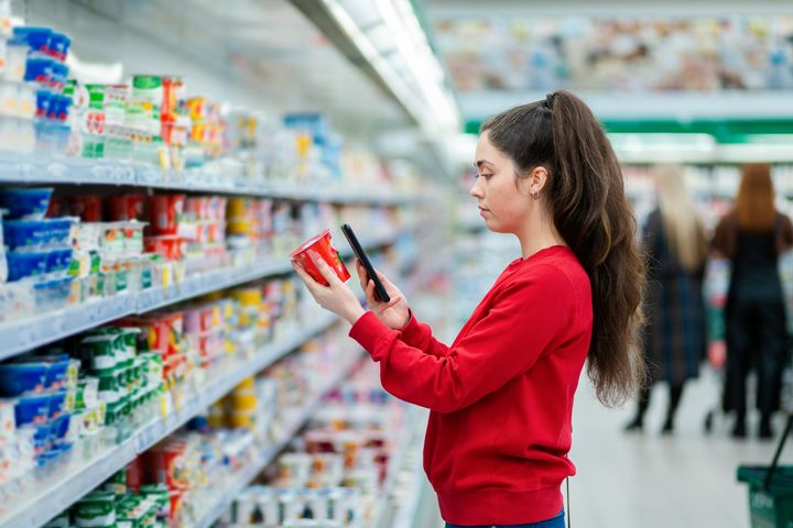 Nainen tarkastelee ruokapakkausta kaupassa.
