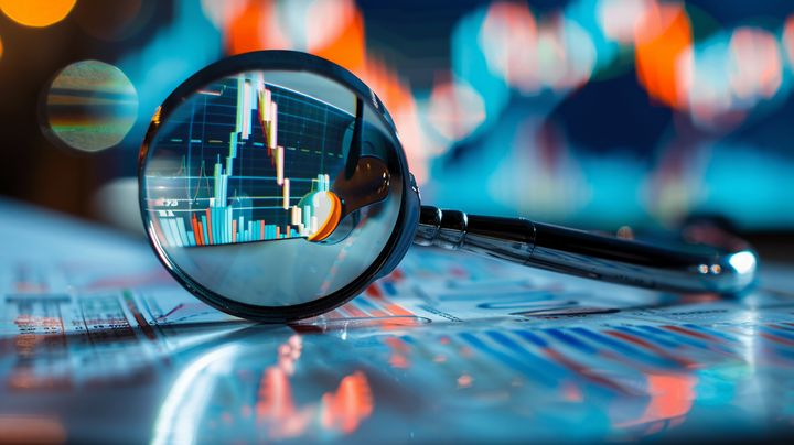 Suurennuslasi näyttää taustalla olevan taloudellisen kaavion, jossa kasvua kuvaava käyrä.