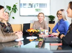 Viisi henkilöä, tilitoimistoammattilaisia, istuu neuvottelupöydän ääressä toimistossa.