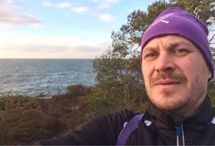 mies katsoo kameraan violetti pipo päässää, keskellä metsäistä maisemaa