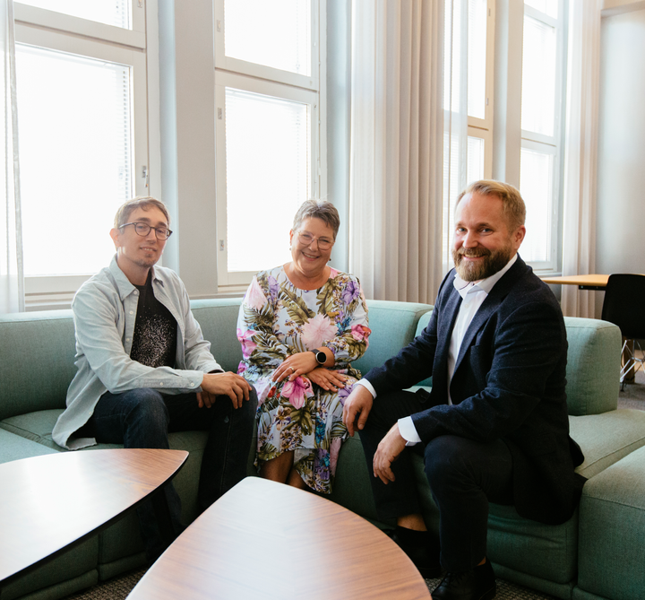 Kolme henkilöä istuu neuvotteluhuoneessa viihtyisällä sohva-alueella.