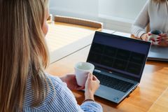 Kaksi henkilöä istuu pöydän ääressä vastakkain, molemmilla kädessään kahvikuppi ja edessään läppäri.