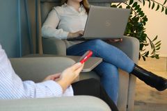 Kaksi henkilöä istuu nojatuoleissa, toisella kädessään puhelin ja toisella sylissään läppäri.