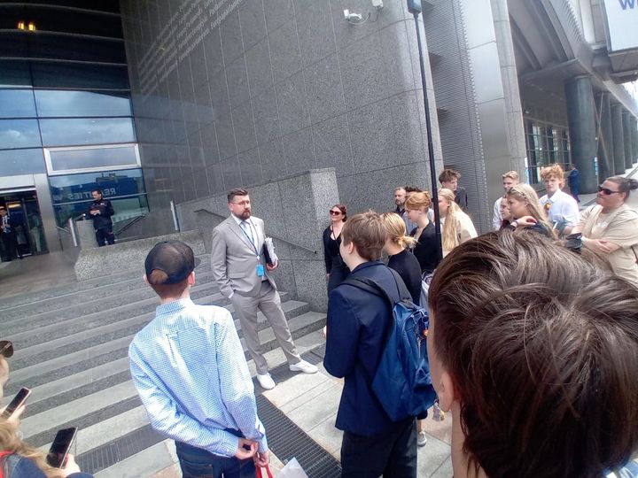 Kuvassa%20henkil%F6%20keskustelemassa%20nuorten%20ryhm%E4n%20kanssa%20rakennuksen%20edess%E4.