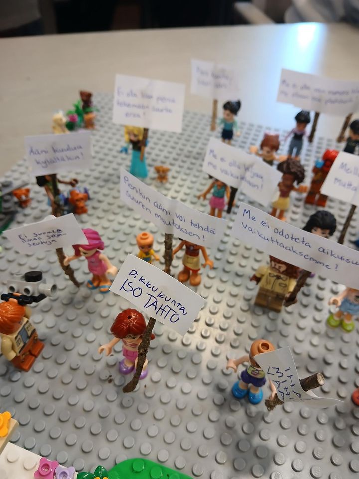 Lego-figuurit%20pit%E4v%E4t%20kylttej%E4%2C%20joissa%20on%20erilaisia%20viestej%E4.