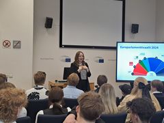 Europarlamentaarikko puhuu nuorille vierailijoille.