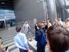 Kuvassa henkilö keskustelemassa nuorten ryhmän kanssa rakennuksen edessä.