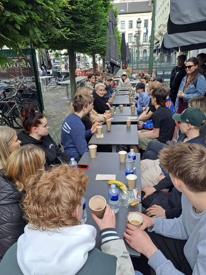 Nuoret%20istuvat%20pitk%E4n%20ulkop%F6yd%E4n%20%E4%E4ress%E4%20keskustelemassa.%20Taustalla%20rakennuksia%20Brysseliss%E4.